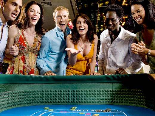 A group of people watching a woman throw dice at a craps table.